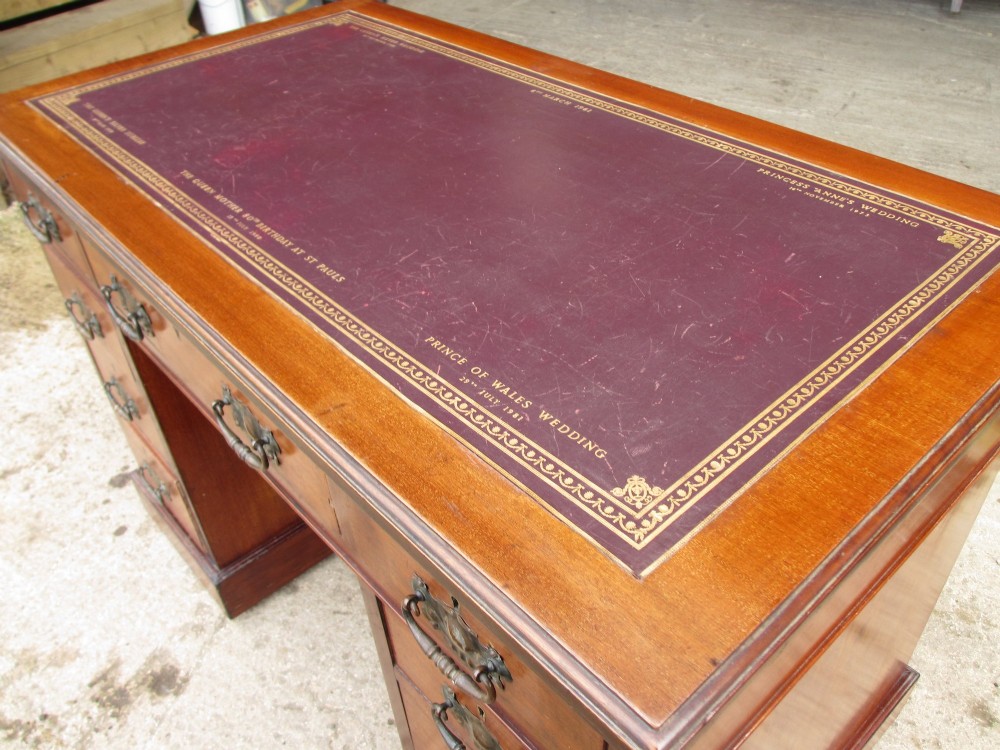 A Victorian walnut pedestal desk featuring nine drawers with brass drop handles and a maroon tooled leather inset writing surface. View VIII