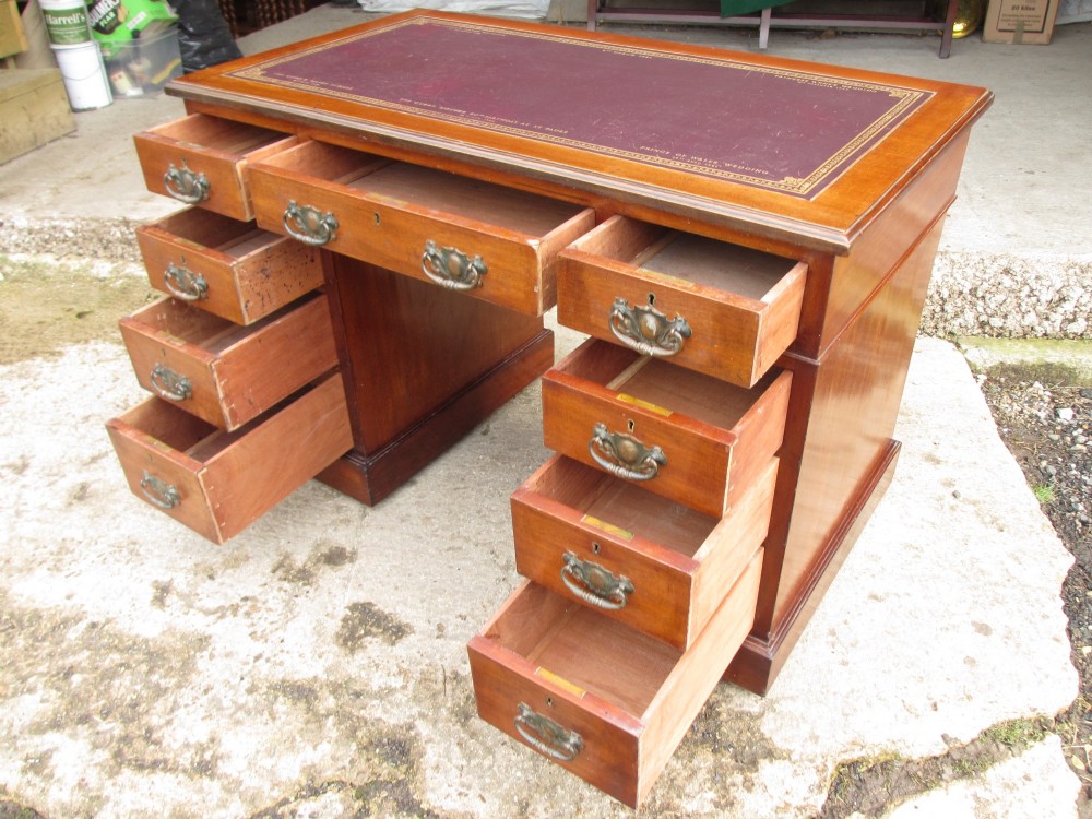 A Victorian walnut pedestal desk featuring nine drawers with brass drop handles and a maroon tooled leather inset writing surface. View XI