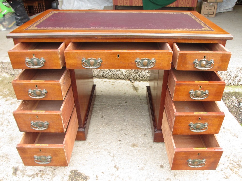 A Victorian walnut pedestal desk featuring nine drawers with brass drop handles and a maroon tooled leather inset writing surface. View XII