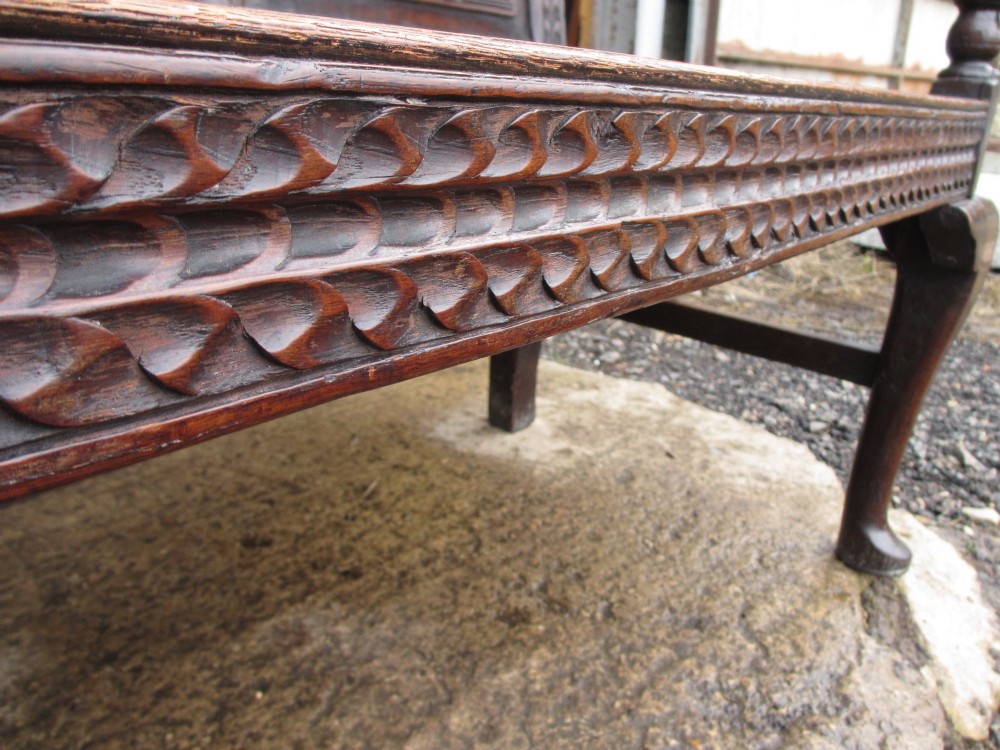 An 18th-century dark oak hall settle featuring four carved arch back panels, curved armrests, and cabriole front legs. View VII