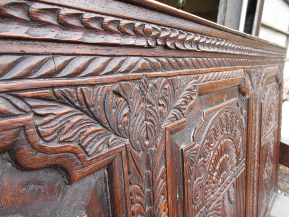 An 18th-century dark oak hall settle featuring four carved arch back panels, curved armrests, and cabriole front legs. View VIII