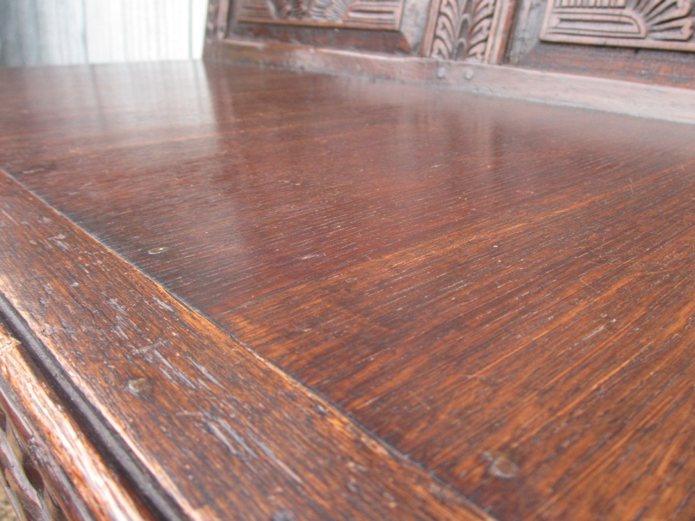 An 18th-century dark oak hall settle featuring four carved arch back panels, curved armrests, and cabriole front legs. View XI