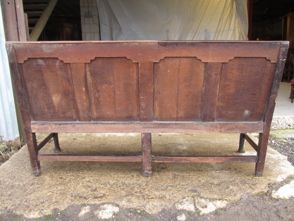 An 18th-century dark oak hall settle featuring four carved arch back panels, curved armrests, and cabriole front legs. View XIV