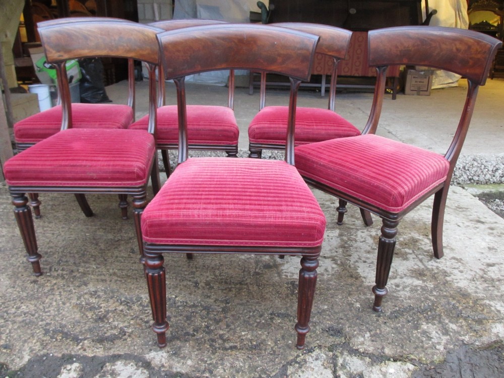 A set of six William IV mahogany dining chairs featuring curved top rails with flame mahogany veneer, reeded turned front legs, and red striped upholstered seats. View IV