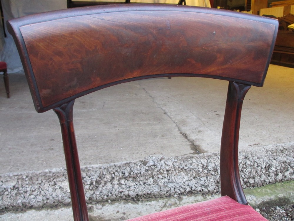 A set of six William IV mahogany dining chairs featuring curved top rails with flame mahogany veneer, reeded turned front legs, and red striped upholstered seats. View IX