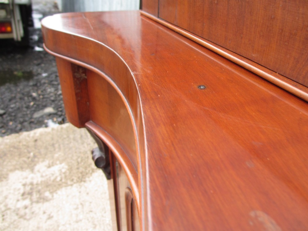 A two-piece Victorian mahogany bookcase featuring an upper section with two glazed doors and carved corbels over a lower cabinet with flame mahogany panelled doors. View VII