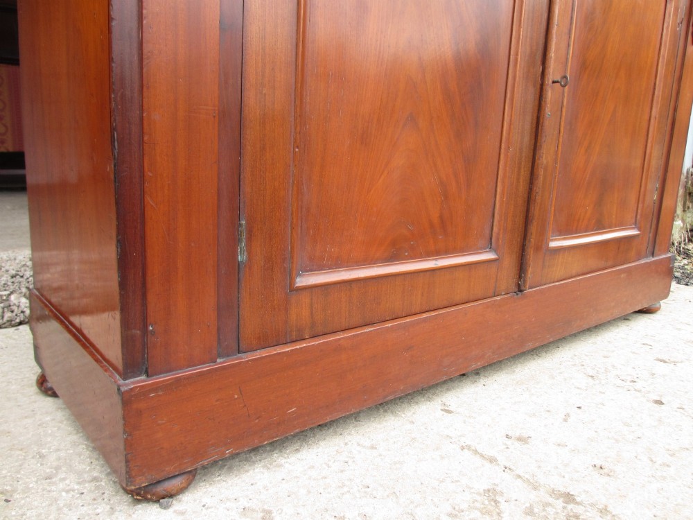 A two-piece Victorian mahogany bookcase featuring an upper section with two glazed doors and carved corbels over a lower cabinet with flame mahogany panelled doors. View IX