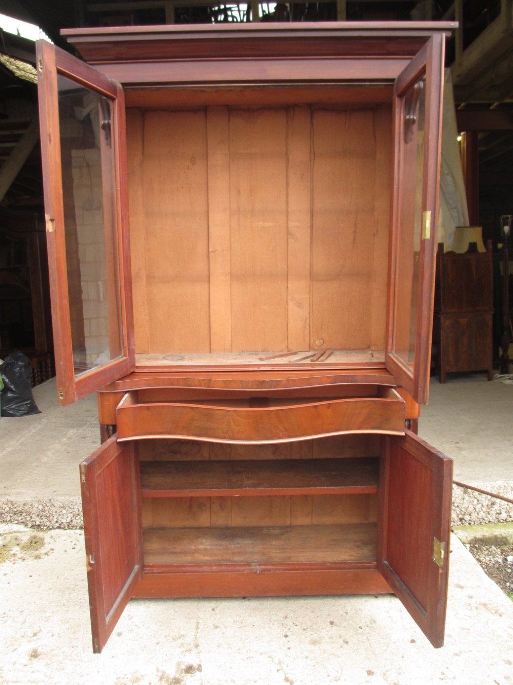 A two-piece Victorian mahogany bookcase featuring an upper section with two glazed doors and carved corbels over a lower cabinet with flame mahogany panelled doors. View X