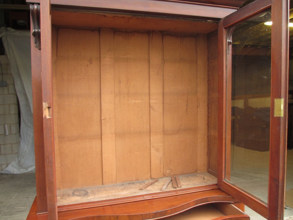 A two-piece Victorian mahogany bookcase featuring an upper section with two glazed doors and carved corbels over a lower cabinet with flame mahogany panelled doors. View XII
