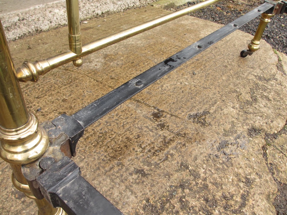 A Victorian brass bed frame featuring circular motifs, vertical spindles, ball finials, and an iron slot frame set on castors. View VIII