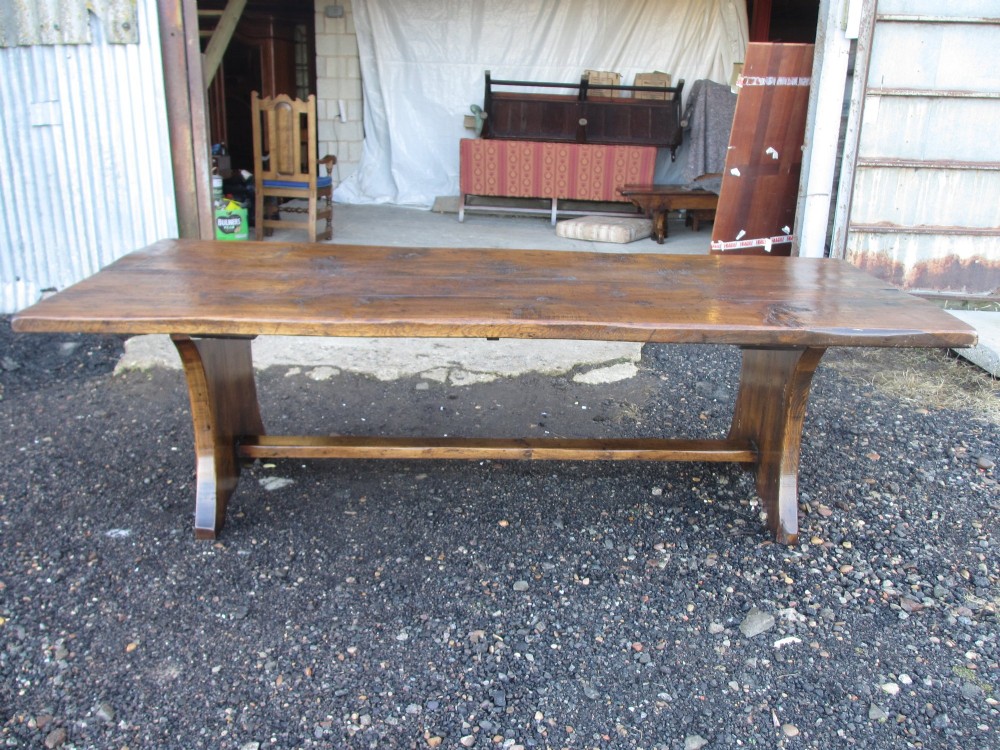 A solid oak refectory dining table with heavy trestle ends, accompanied by matching long wooden bench forms. View VIII