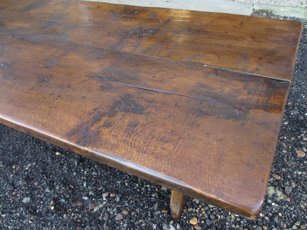 A solid oak refectory dining table with heavy trestle ends, accompanied by matching long wooden bench forms. View XII