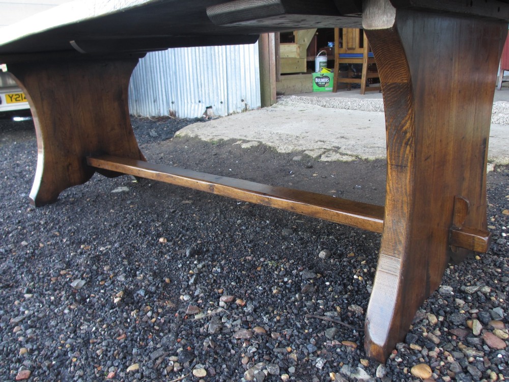 A solid oak refectory dining table with heavy trestle ends, accompanied by matching long wooden bench forms. View XIII