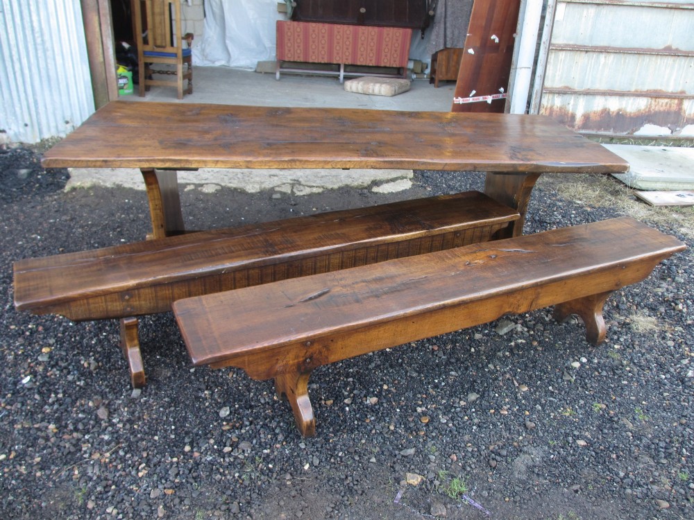 A solid oak refectory dining table with heavy trestle ends, accompanied by matching long wooden bench forms. View XV