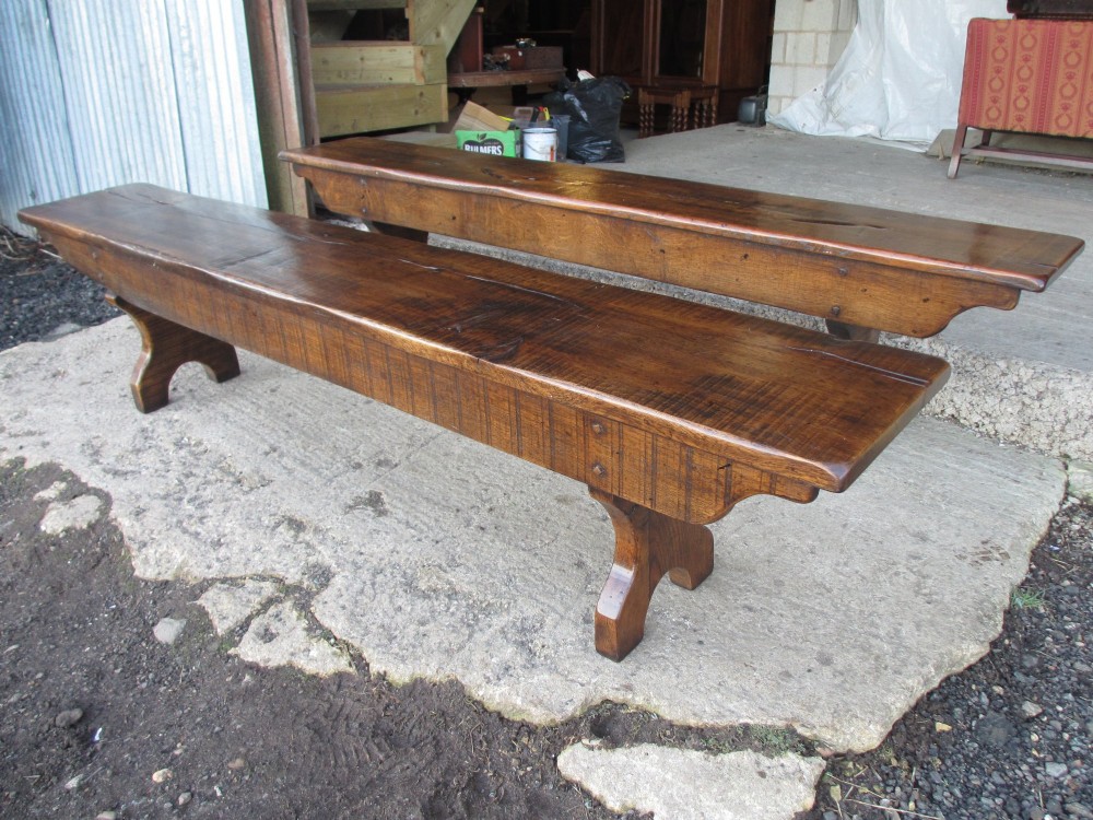 A long Edwardian solid oak bench featuring a rectangular seat and shaped trestle end supports. View II