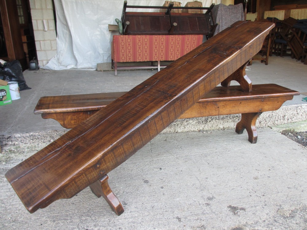 A long Edwardian solid oak bench featuring a rectangular seat and shaped trestle end supports. View IV