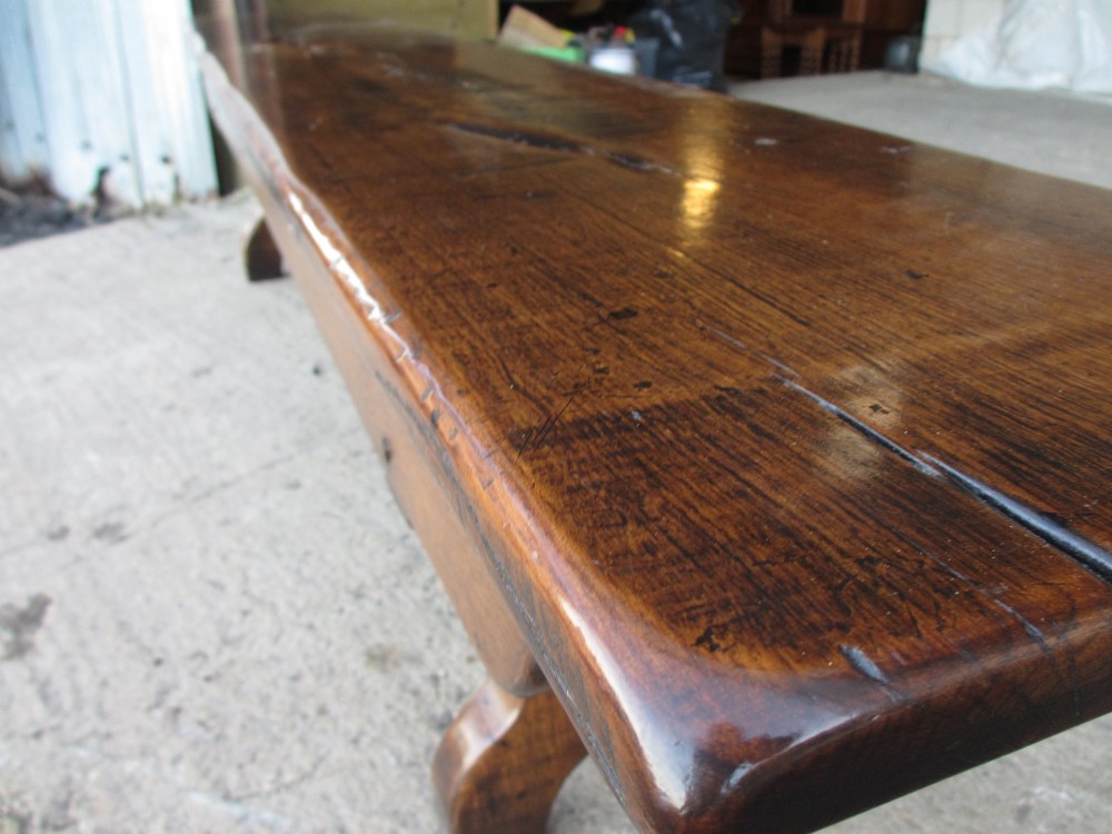 A long Edwardian solid oak bench featuring a rectangular seat and shaped trestle end supports. View IX