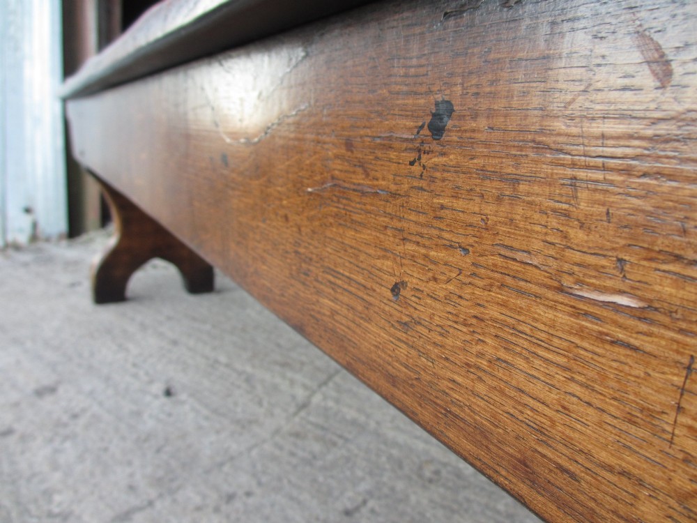 A long Edwardian solid oak bench featuring a rectangular seat and shaped trestle end supports. View XIII