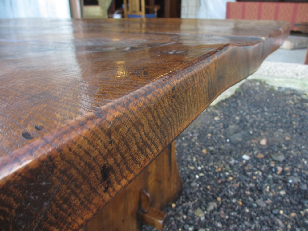 A solid oak refectory dining table featuring a thick plank top, shaped trestle ends, and a low central stretcher. View IX