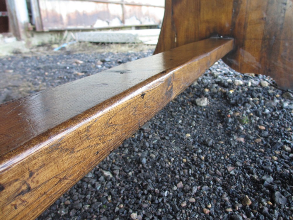 A solid oak refectory dining table featuring a thick plank top, shaped trestle ends, and a low central stretcher. View XII