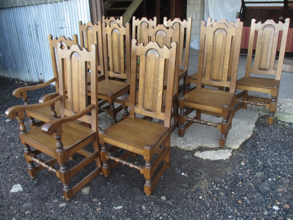 A set of twelve 20th-century oak high-back dining chairs with arched panel backrests and blue upholstered seat pads. View IV