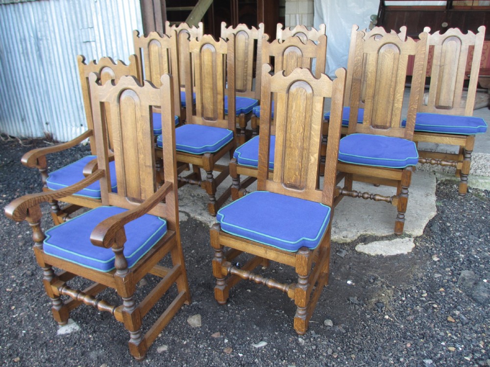 A set of twelve 20th-century oak high-back dining chairs with arched panel backrests and blue upholstered seat pads. View VII
