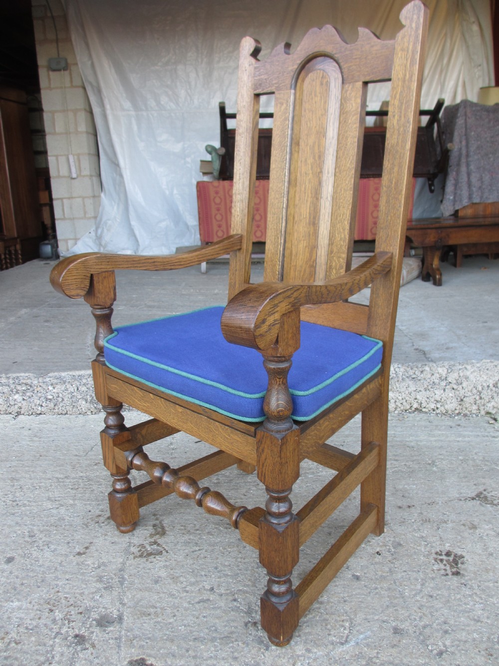 A set of twelve 20th-century oak high-back dining chairs with arched panel backrests and blue upholstered seat pads. View IX