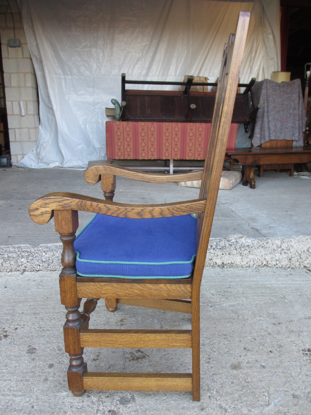 A set of twelve 20th-century oak high-back dining chairs with arched panel backrests and blue upholstered seat pads. View XI
