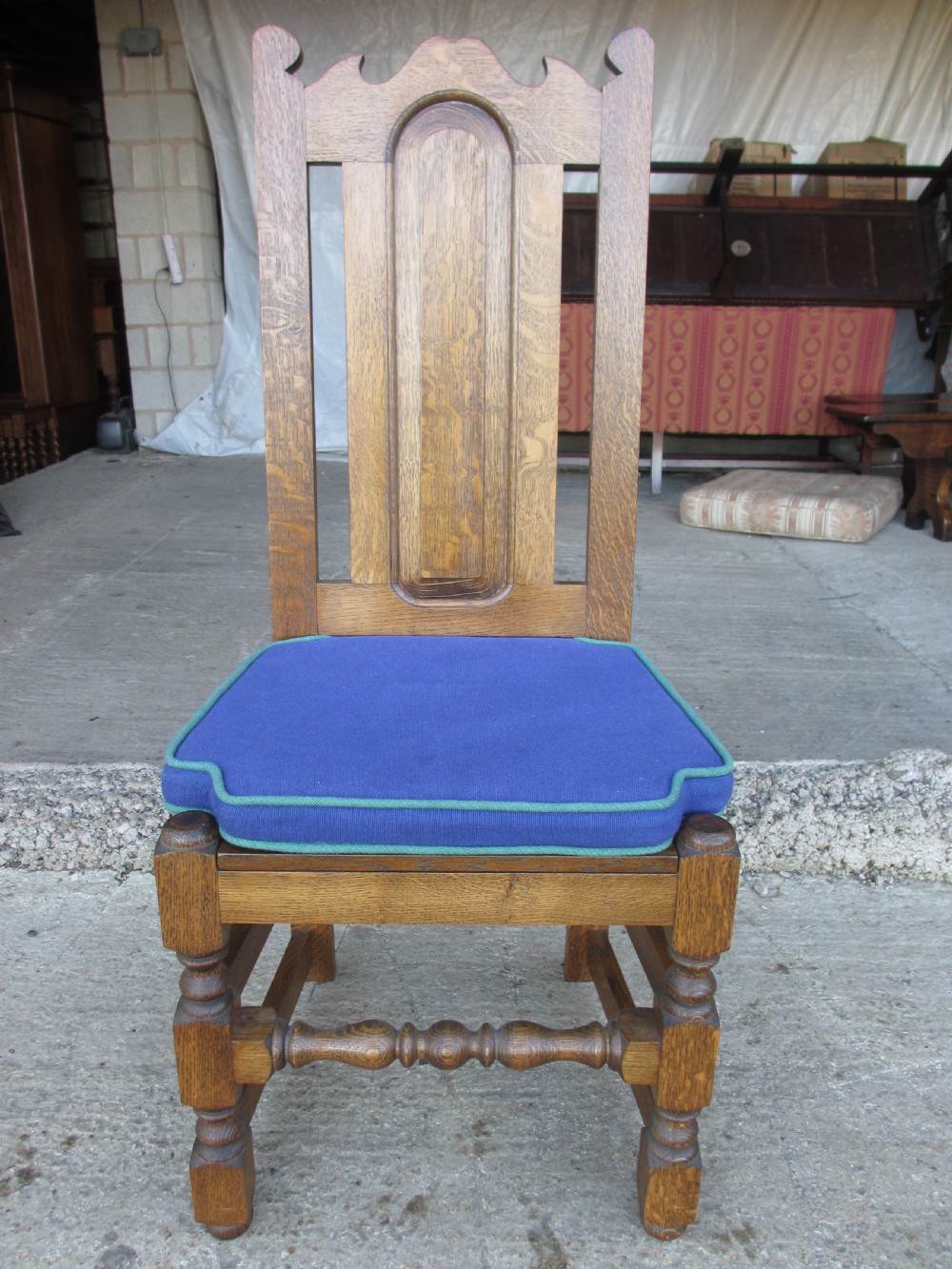 A set of twelve 20th-century oak high-back dining chairs with arched panel backrests and blue upholstered seat pads. View XIV