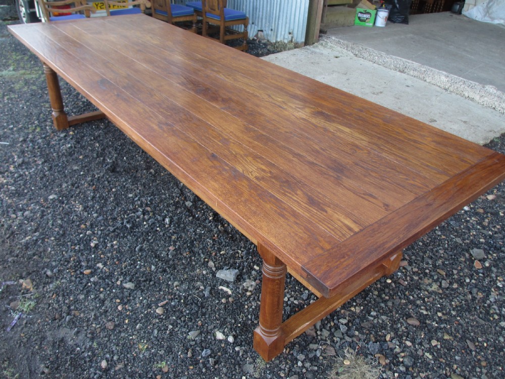 An eleven-foot oak refectory dining table with a planked top, low stretcher base, and heavy turned legs. View IV