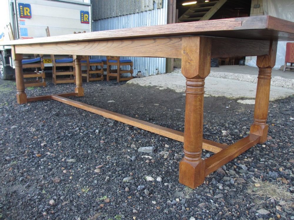 An eleven-foot oak refectory dining table with a planked top, low stretcher base, and heavy turned legs. View IX
