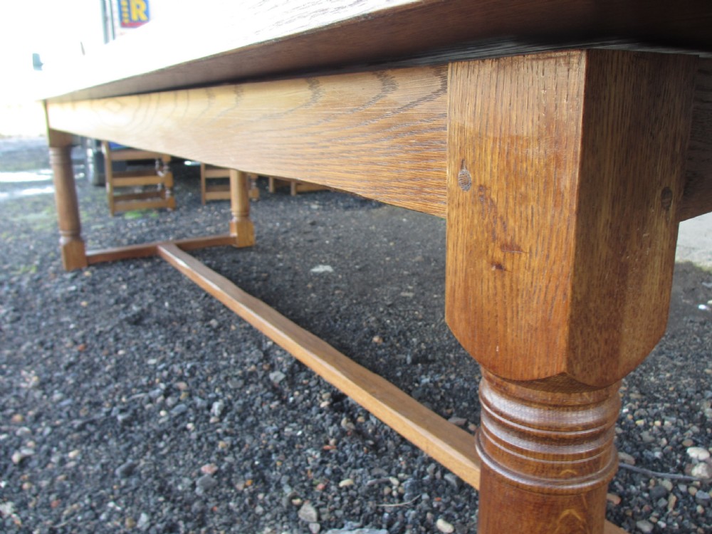 An eleven-foot oak refectory dining table with a planked top, low stretcher base, and heavy turned legs. View XII