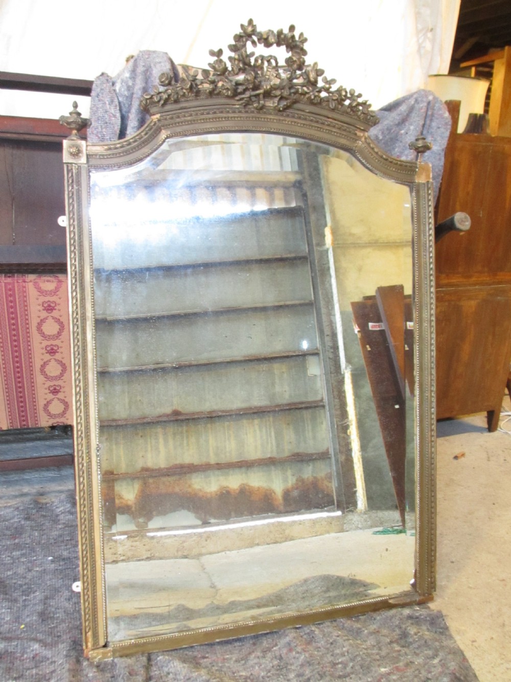 An arched giltwood overmantel mirror with an ornate floral cresting and beaded border details. View II