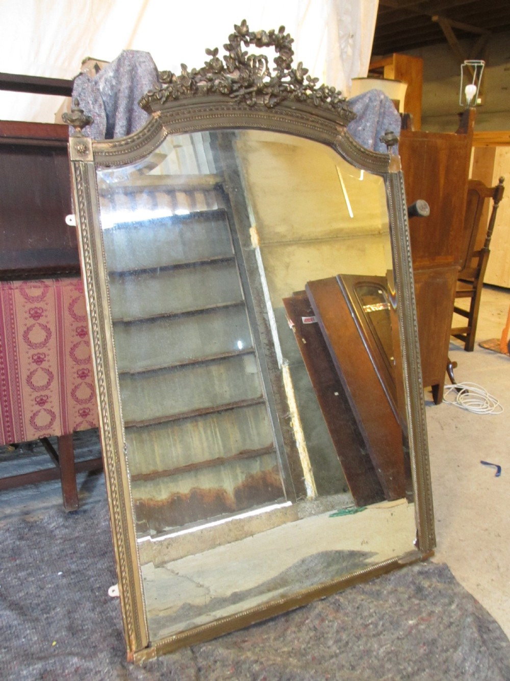 An arched giltwood overmantel mirror with an ornate floral cresting and beaded border details. View IV