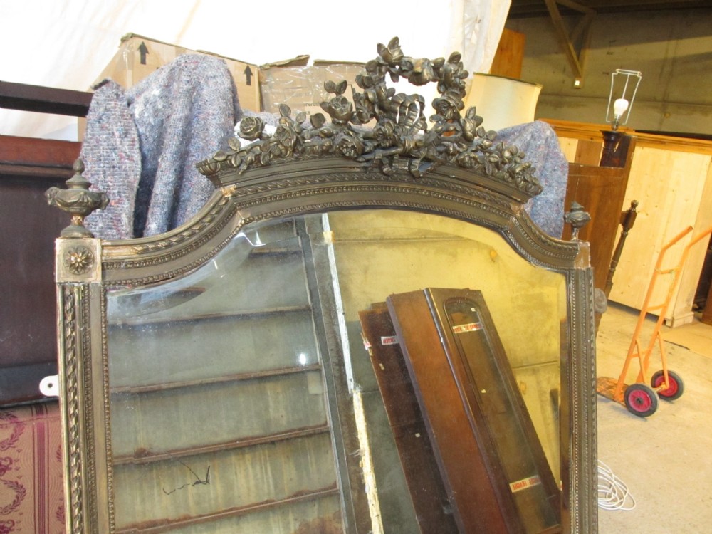 An arched giltwood overmantel mirror with an ornate floral cresting and beaded border details. View V