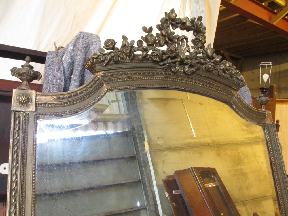 An arched giltwood overmantel mirror with an ornate floral cresting and beaded border details. View VI