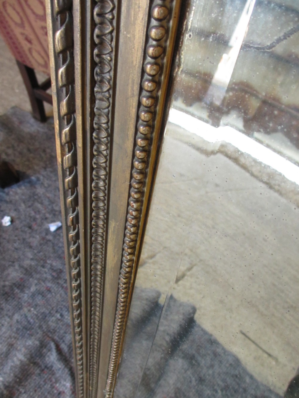 An arched giltwood overmantel mirror with an ornate floral cresting and beaded border details. View VIII