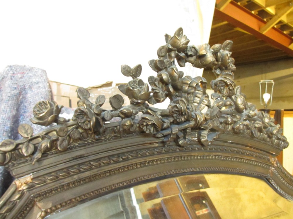 An arched giltwood overmantel mirror with an ornate floral cresting and beaded border details. View IX