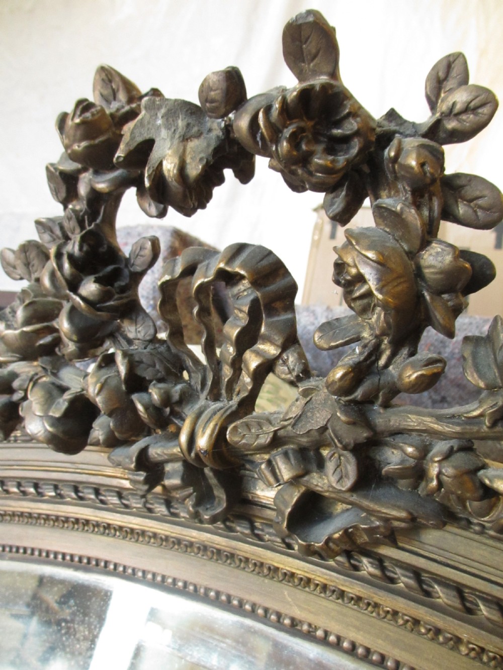 An arched giltwood overmantel mirror with an ornate floral cresting and beaded border details. View X
