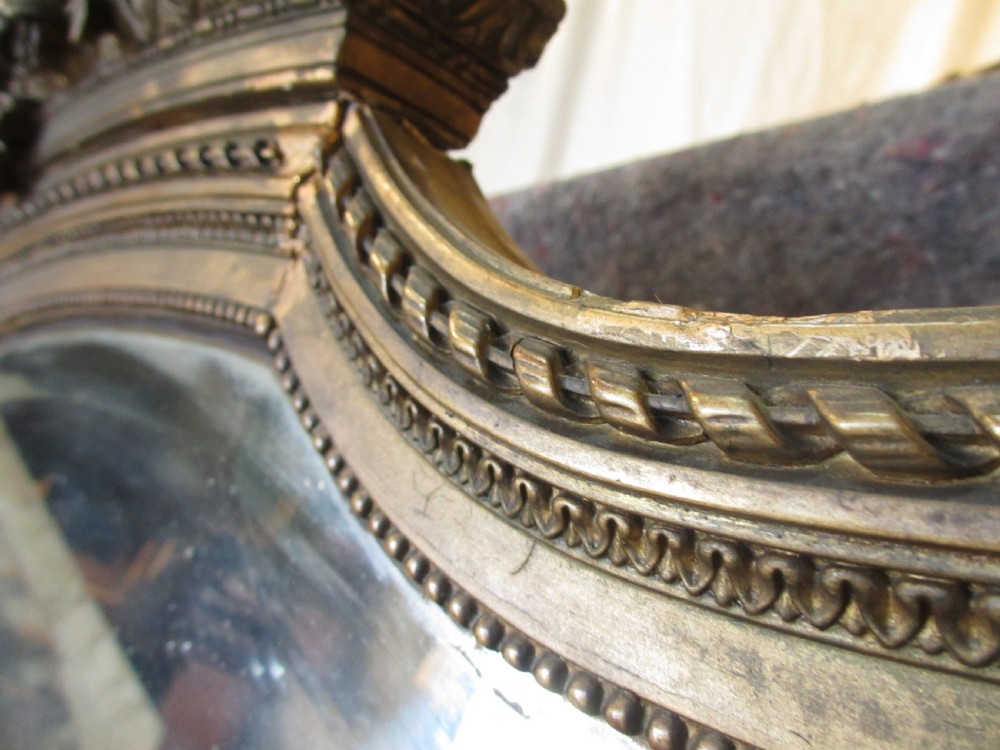 An arched giltwood overmantel mirror with an ornate floral cresting and beaded border details. View XII