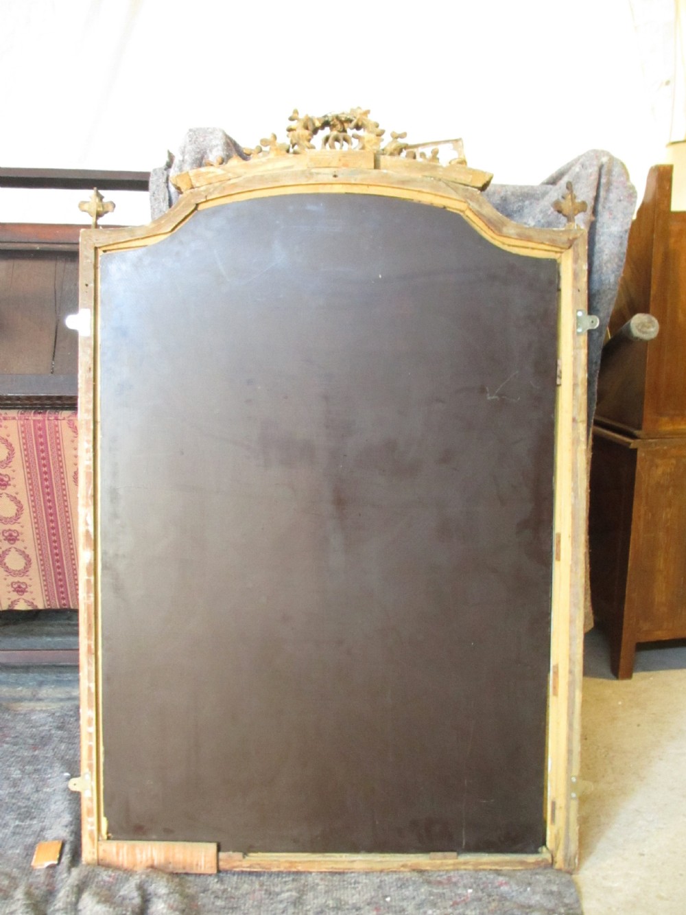 An arched giltwood overmantel mirror with an ornate floral cresting and beaded border details. View XV