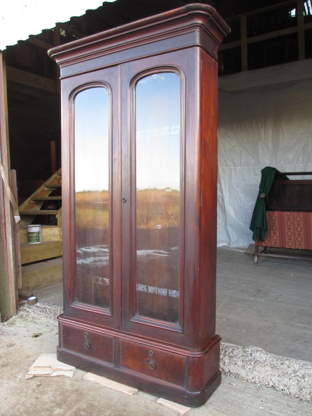 A tall 19th-century mahogany glazed bookcase featuring two long arched glass doors above a base fitted with two drawers. View II