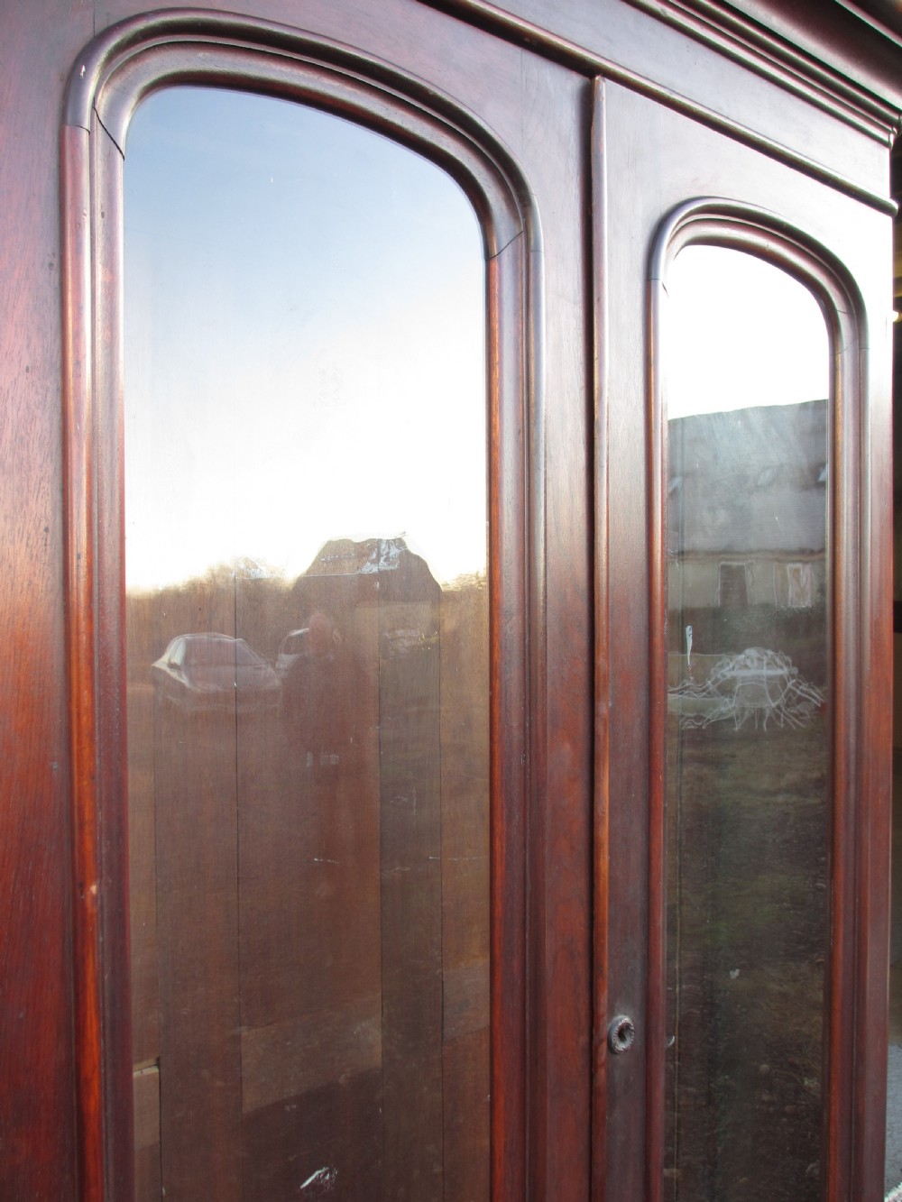 A tall 19th-century mahogany glazed bookcase featuring two long arched glass doors above a base fitted with two drawers. View V