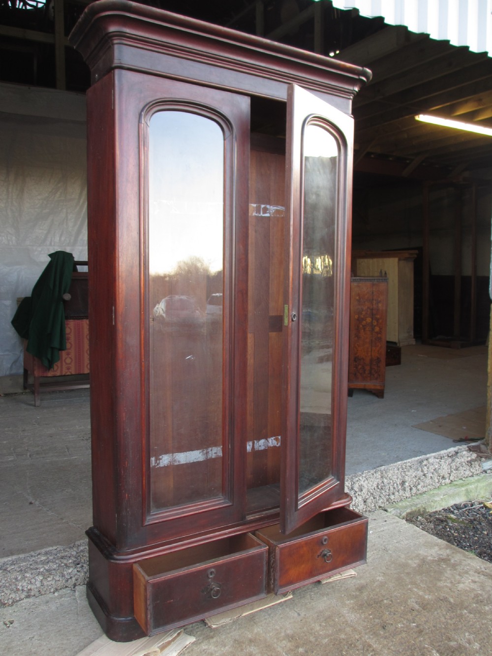 A tall 19th-century mahogany glazed bookcase featuring two long arched glass doors above a base fitted with two drawers. View XV