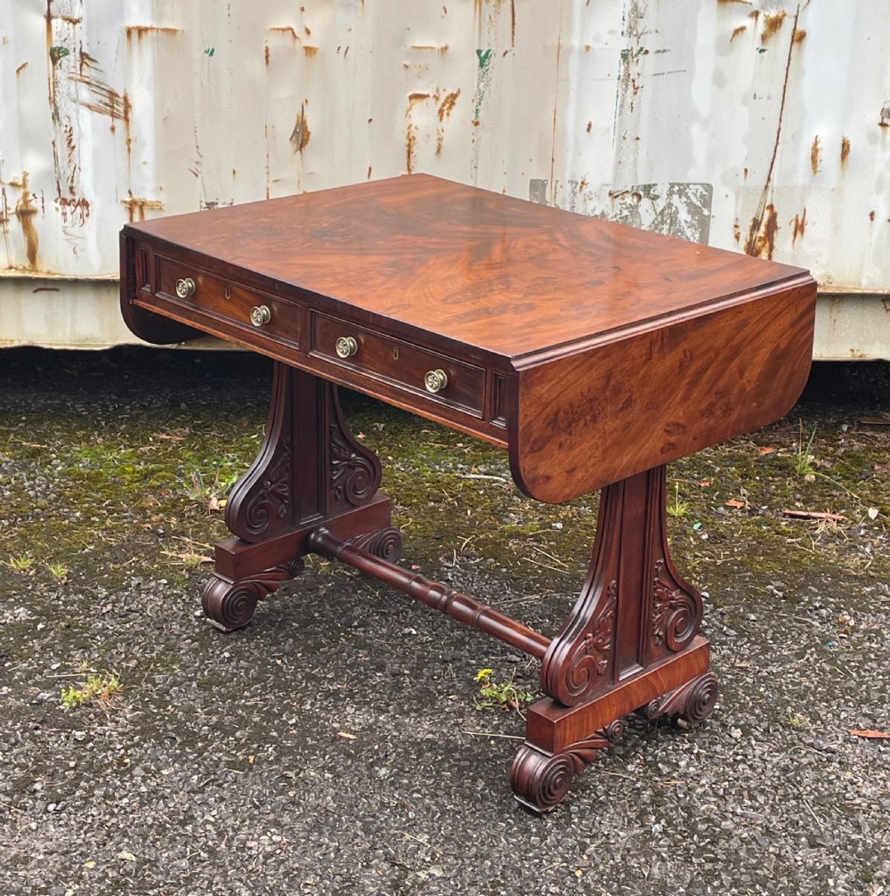 A William IV mahogany sofa table with two drop-leaf ends, frieze drawers with round brass knobs, and carved scroll trestle supports. View II