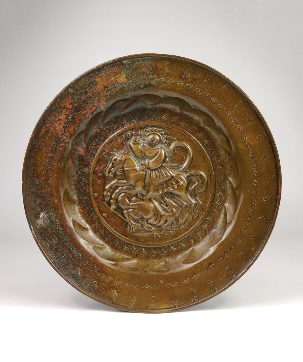 A 16th century alms dish depicting George and the dragon. 